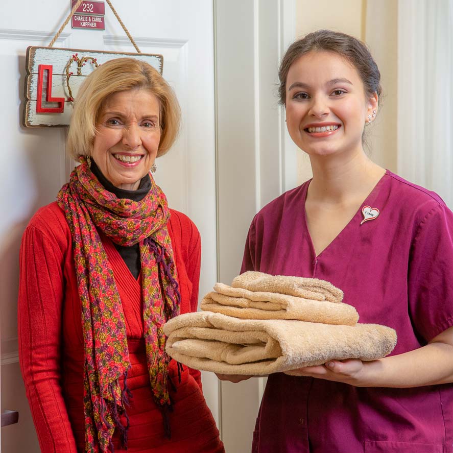 A team member delivering fresh linens to a resident at Osprey Heights